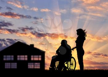 Silhouette of a nurse caring for a disabled person in a wheelchair. Concept of caring for a disabled person and the house of aged