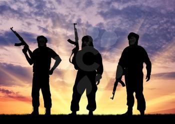 Silhouette of three terrorists with a weapon against a background of sunset 
