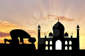 Concept of religion is Islam. Silhouette of man praying at sunset, and the mosque
