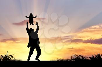 Silhouette of a happy father throws the baby into the sky
