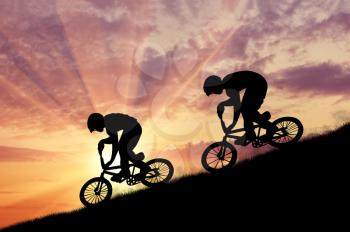 Concept of extreme sports. Silhouette of two moving cyclists at sunset