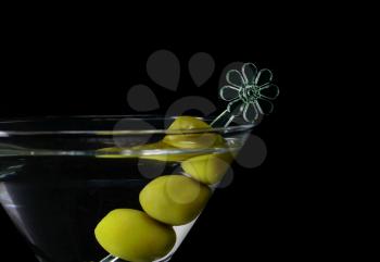 Martini cocktail with olives on a black background closeup