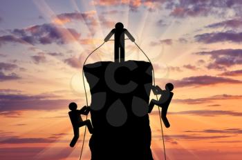 Climber helps ascent of two climbers on a mountain top. Concept of teamwork and trust