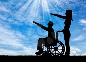 Silhouette of a disabled man in a wheelchair and his wife have a good time. The concept of caring and supporting disabled people in the family