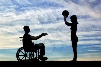 Silhouette of a disabled man in a wheelchair and his wife playing ball together. The concept of caring and supporting disabled people in the family