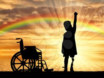 A happy child is a disabled girl with a prosthetic leg in the open air at sunset near the sea, and a wheelchair. The concept of children with prosthetic leg
