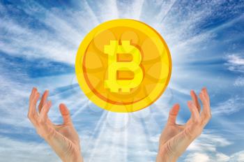 Bitcoin against the sky above the hands. The concept of crypto currency