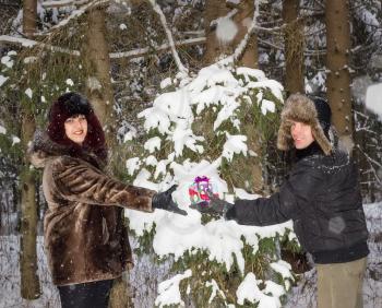 The happy man gives the girl a bright box with a gift.