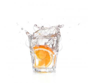 orange splashing into glass of water on white background