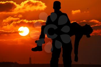 silhouette of a soldier officer man holding on hands girl woman. The concept of war, victim