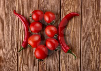 Red hot cherry and chili peppers over white wooden background