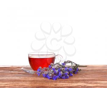 Herbal tea in a glass cup, fresh flowers on a background of wooden boards