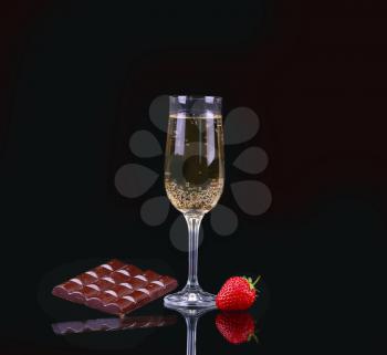 Glass of cold champagne with strawberries on a black background