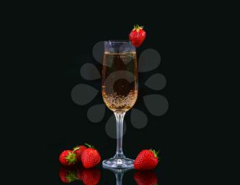 Glass of cold champagne with strawberries on a black background