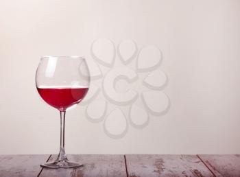 a glass of red wine and glasses on a wooden table. Gray background
