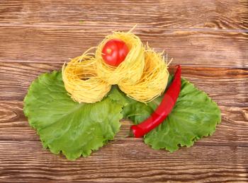 Pasta on the wooden background with tomato, pepper lettuce and pepper