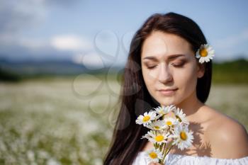 Beautiful woman on a flower granden enjoying her time outdoors. pretty girl relaxing outdoor, having fun, holding plant, happy young lady and spring green nature, harmony concept