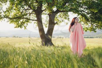 Beauty Romantic Girl Outdoors. Beautiful Teenage Model Dressed in Long Pink Dress on the Field in Sun Light. Blowing Long Hair. Autumn. Glow Sun, Sunshine. Backlit. Toned in warm colors