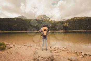Young man looking at Black Lake, Durmitor National Park, Zabljak, Montenegro. Hipster traveler enjoying view of Black Lake