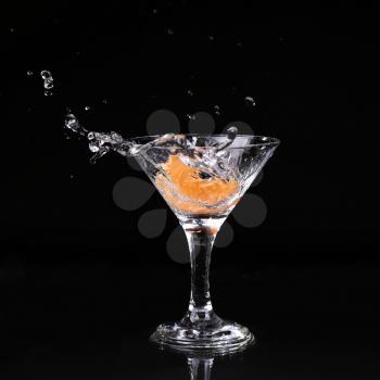 martini cocktail splashing into glass on black background