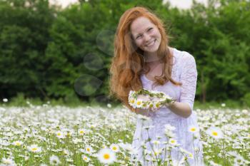 Beautiful woman enjoying daisy field, nice female in the meadow of flowers, pretty girl relaxing outdoor, having fun,holding plant, happy young lady and spring green nature, harmony concept