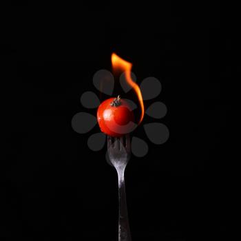 cooking and food concept - female hand  with fork and tomato