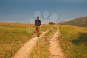 Young man walking on a countryside road.