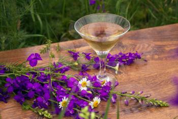 Wine glass against rural landscape, flower collection