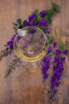 Wine glass against rural landscape, flower collection