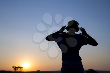 Silhouette young woman with headphone on sunrise background.