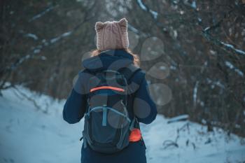 girl standing in a snowy mountain forest with a backpack on the road in search of