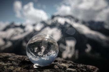 Transparent glass sphere and snow-capped peaks in the background. Concept and idea of travel