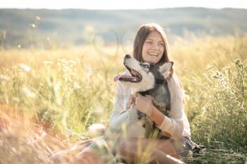 Beautiful young woman playing with funny husky dog outdoors at park. Summertime and sunset