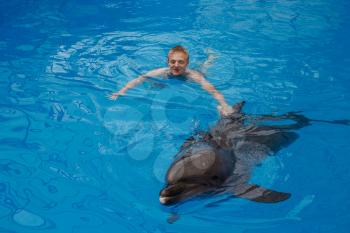 happy man swim with dolphin in dolphinarium