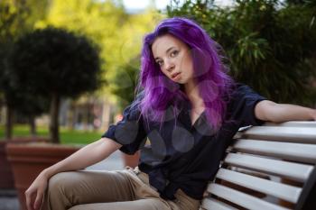 Beautiful young violet hairy girl walking at sunset in a city park. St. Petersburg, New Holland