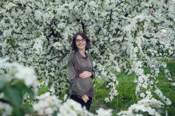 A young pregnant woman in an apple orchard in the heart of Warsaw. Relaxing in the spring in Poland