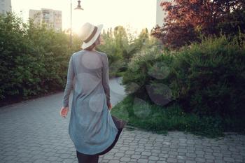 A beautiful pregnant young woman enjoys an evening walk through a beautiful green park. Warsaw Poland
