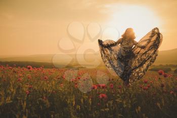 Young beautiful woman in spring field. concept of freedom. walking in amazing poppy field. Warm sunset colors. Soft colors.