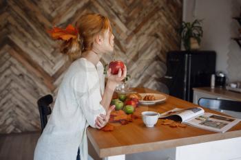 Autumn sseries in the Kitchen, melancholy and warm.. Relaxing in cold weather. red-haired girl enjoying apples in the kitchen