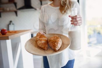 Autumn sseries in the Kitchen, melancholy and warm.. Relaxing in cold weather. red-haired girl holding a tray with pastries and bottle of milk