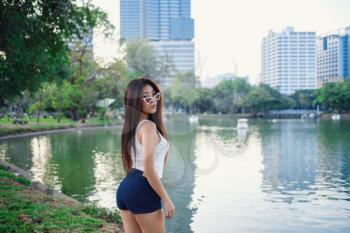 Summer sunny lifestyle portrait of young stylish hipster woman walking on the street, wearing cute trendy outfit. Young Asian women tourist traveler smiling in bangkok. street fashion