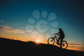 Silhouette of a male mountainbiker at sunset in the mountains. The idea and concept of a healthy lifestyle, outdoor activities and sports