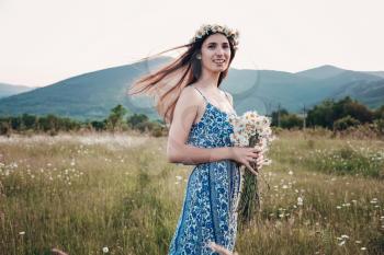 Beautiful woman enjoying field, pretty girl with long dark hair relaxing outdoor, having fun, holding plant, happy young lady and spring green nature, harmony concept