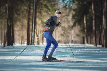 Cross-country skiing woman doing classic nordic cross country skiing in trail tracks in snow covered forest. Training track for skiers in the park of Moscow, Odintsovo