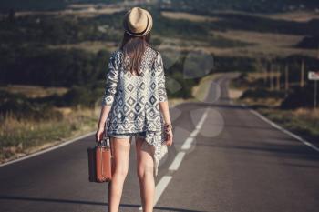 women is hailing a car on a road. Thumbing a ride. Outdoors vacation..