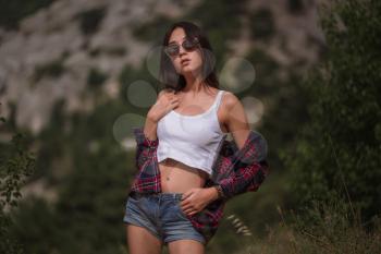 Beautiful young woman travels through a mountainous area. The concept and idea of a summer holiday, hitchhiking, finding your own way