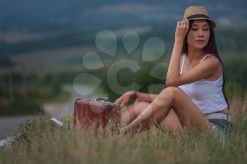 women is hailing a car on a road. Thumbing a ride. Outdoors vacation. Asian