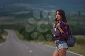 women is hailing a car on a road. Thumbing a ride. Outdoors vacation. Asian