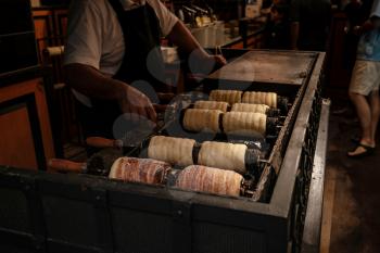 Trdelnik bakery on the street market in Prague. Close-up. Street food. Trdelnik is tubes of sweet dough, cooked on an open fire. Selective focus.