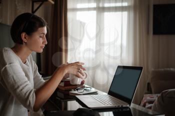 Smiling young asian woman video calling on laptop. Back view photo student looking at computer screen watching webinar or doing video chat by webcam. Over shoulder close up mock up screen view.